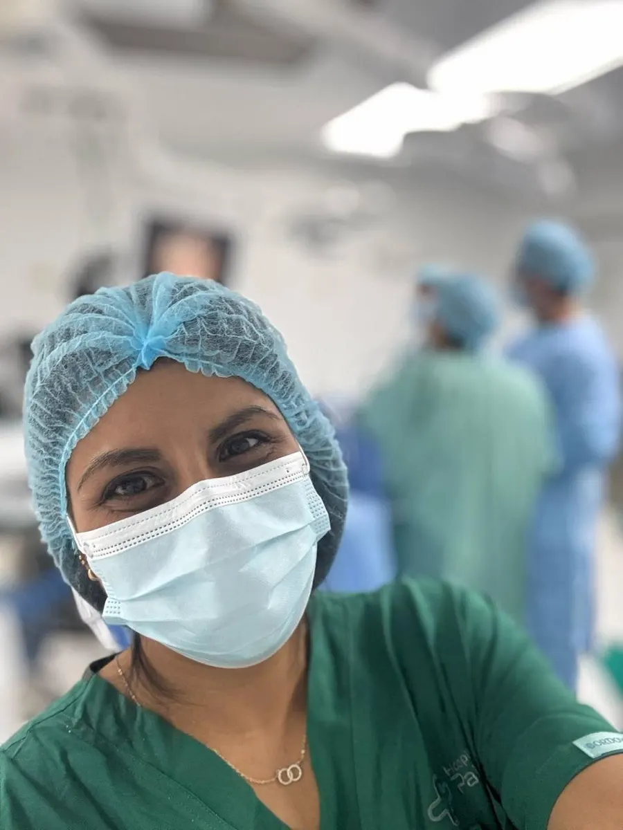 Our photographer in the foreground inside an operating theatre, with the surgical team working behind her